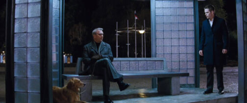 En una escena nocturna con el fondo de la imagen prácticamente negra por la oscuridad, dos hombres hablan en un banco que parece estar bajo una estructura de columnas de teselas de cristal. El propio banco tiene su respaldo bajo hecho con las mismas teselas. Uno de los hombres está sentado en el banco, con brazos y piernas cruzadas, vestido con una gabardina de piel y llena un perro golden retriever sentado al lado. A la derecha se encuentra otro hombre, con pantalones y abrigo de tres cuartos negros, que lo mira con sorpresa. No tienen aspecto de ser una familia normal, pero sí podría ser un encuentro común entre personajes de Cyberpunk o Walküre.