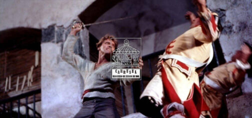 Fotograma de El temible burlón, en el que con una vista en contrapicado Burt Lancaster, con expresión de mala pipa y vestido con una camisa gris, cinturón rojo y pantalón azul, despacha con un estoque sobre la cabeza a dos guardias con casacas amarillas y rojas. Está aquí porque las de piratas son buenas ambientaciones para empezar en el rol. En el centro sobre la foto está el logo de la iniciativa Carrusel: un rectángulo vertical con un tiovivo de feria coronado por un dado de 20 caras, cuyas monturas son una imagen de Cthulhu, un caballero armado a caballo y una armadura de combate tecnológica. Bajo el tiovivo aparecen las letras grandes CARRUSEL ondulando arriba y abajo, y bajo esas, ocupando el mismo ancho, BLOGUERO DE JUEGOS DE ROL.