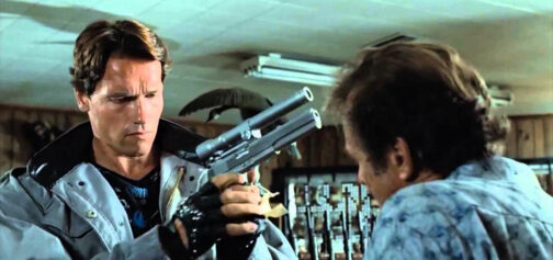 El Terminator de la primera película sostiene entre sus manos una pistola AMT Hardballer .45 Longslide con un puntero láser hecho a medida, ante la atenta mirada del vendedor que no se hace a la idea de que va a cobrar en plomo. Una escena que ha inspirado no pocas opciones de los accesorios para armas en Tipos Duros con Savage Worlds.