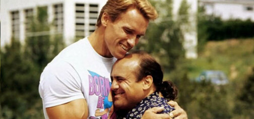 Arnold Schwarzenegger, con camiseta blanca con un estampado horteramente ochentero en colores magenta y azul, abraz a Danny DeVito, con una camisa blanca con unos motivos repetitivos de formas blancas sobre fondo azul oscuro, durante el rodaje de Los gemelos golpean dos veces.