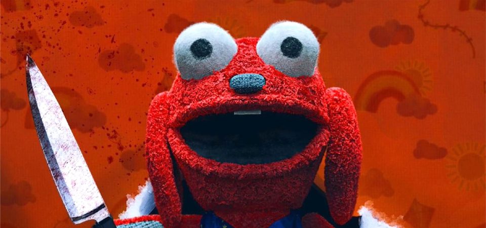 Primer plano de la cara de Benny, el arrollador protagonista absoluto de la película slasher Benny Loves You (Benny te ama). Es un peluche de color rojo intenso, con nariz achatada negra, enormes ojos saltones que sobresalen por encima de la frente, la boca abierta en lo que resulta una sonrisa mona y una tira de trapo haciendo las veces de sus dos únicos dientes, las paletas de arriba. A los lados de la cabeza le cuelgan dos largas orejas como las de un perro orejón. Es un peluche de aspecto feo pero simpático a pesar de que se ve que sostiene un cuchillo ensangrentado.