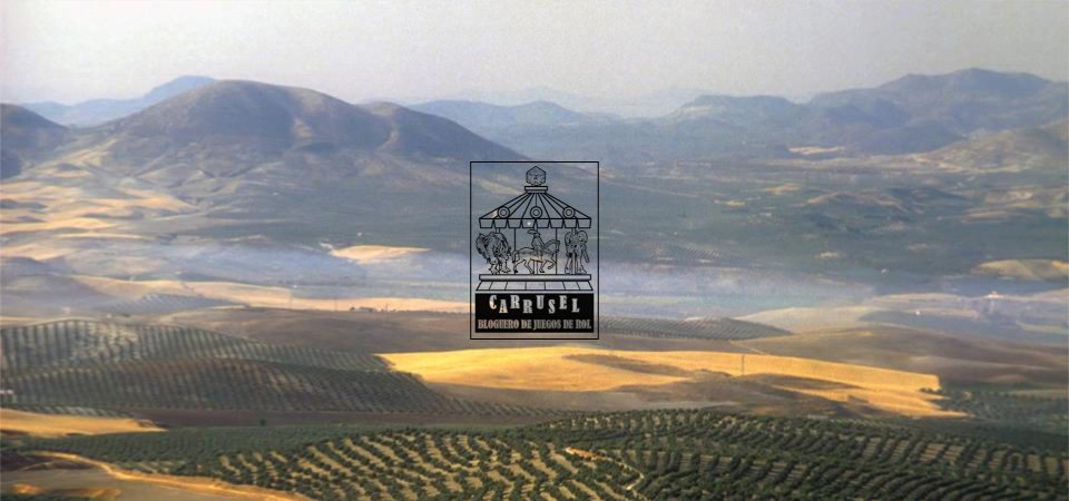 Fotografía de un bonito paisaje de los cerros de Úbeda, cubiertos de plantíos de olivo y zonas amarillentas en barbecho, cubiertas por una ligera neblina hasta el horizonte plagado de montañas de relieve suave. En el centro sobre la foto está el logo de la iniciativa Carrusel: un rectángulo vertical con un tiovivo de feria coronado por un dado de 20 caras, cuyas monturas son una imagen de Cthulhu, un caballero armado a caballo y una armadura de combate tecnológica. Bajo el tiovivo aparecen las letras grandes CARRUSEL ondulando arriba y abajo, y bajo esas, ocupando el mismo ancho, BLOGUERO DE JUEGOS DE ROL.