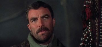 Fotograma de alguna película de Tom Selleck con un primer plano de su cara mirando hacia un lado de la cámara. Tiene el pelo corto y su clásico bigote, además de barba de varios días. En Wildpring, la serie en la que se basa Tipos Duros, era el actor elegido para interpretar a Frank Castillo. La imagen ilustra a Castillo como personaje pregenerado de Savage Worlds.