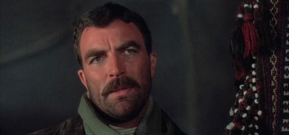 Fotograma de alguna película de Tom Selleck con un primer plano de su cara mirando hacia un lado de la cámara. Tiene el pelo corto y su clásico bigote, además de barba de varios días. En Wildpring, la serie en la que se basa Tipos Duros, era el actor elegido para interpretar a Frank Castillo. La imagen ilustra a Castillo como personaje pregenerado de Savage Worlds.