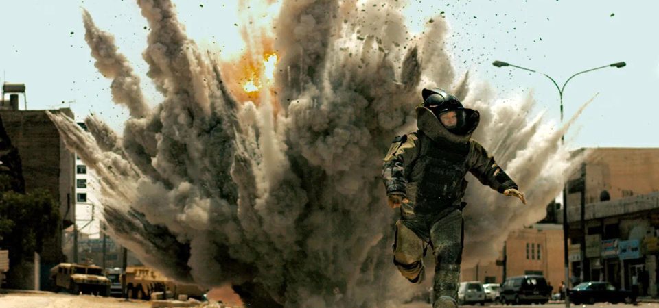 A plena luz del día, bajo un cielo azul claro, en medio de una calle de oriente medio a cuyo fondo se pueden ver una serie de coches civiles así como un humvee y un transporte de tropas blindado. Un artificiero corre hacia el espectador como buenamente puede, ataviado con su grueso traje antifragmentación, en el momento en que la explosión de una bomba levanta una enorme y densa nube de polvo y trozos de metralla en todas direcciones. Es un fotograma de la película En tierra hostil (The Hurt Locker), que ilustra perfectamente una situación habitual manejando explosivos en Savage Worlds y Tipos Duros.