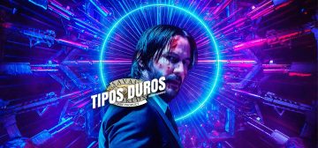Imagen de primer plano de John Wick, con el cuerpo de perfil y la cara girada a la derecha, mirando al espectador. Tiene varias heridas y magulladuras en la cara. Rodeando la cabeza hay un halo de neón azúl, mientras que docenas de armas largas de fuego, iluminadas por una intensa luz magenta y azul, le apuntan a la cabeza. Entre el halo y las líneas de las armas se crea un efecto de líneas de luminosas que asemeja a las aureolas de santidad de los santos de la Iglesia. Sobre la imagen está impreso el logo de Tipos Duros, el juego de rol: el texto Tipos Duros en letras blancas grandes y cuadradas, con una inclinación de unos 15º hacia la derecha y debajo, letra más pequeña pero con las mismas características Edición Aventura, todo girado unos 15º a contrarreloj y superpuesto al logo de Savage Worlds Fans Product.