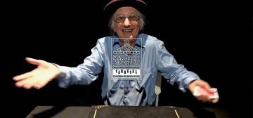 Una fotografía del mago cartomante Juan Tamaríz, sobre un fondo negro, con las manos separadas y una baraja en la mano izquierda. Está frente a una mesa, lleva un sombrero morado y una camisa azul cielo. Éste sí que sabía de hacer trucos del DJ y lo demás son tonterías. En el centro sobre la fotografía está el logo de la iniciativa Carrusel: un rectángulo vertical con un tiovivo de feria coronado por un dado de 20 caras, cuyas monturas son una imagen de Cthulhu, un caballero armado a caballo y una armadura de combate tecnológica. Bajo el tiovivo aparecen las letras grandes CARRUSEL ondulando arriba y abajo, y bajo esas, ocupando el mismo ancho, BLOGUERO DE JUEGOS DE ROL.