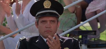 Un teniente de la policía metropolitana. Un hombre de mediana edad, con las sienes y pobladas cejas canosas, perfectamente afeitado y expresión de mal humor. Viste un uniforme de policía de color azul muy oscuro y gorra del mismo color. Lleva emblemas de la Policía Metropolitana, de color blanco y plata en la chaqueta y dorado en la gorra. Lo que podría ser un ejemplo de oficial de policía para Savage Worlds.