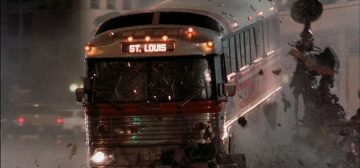 En una imagen urbana nocturna un clásico autobús de película estadounidense, en color metal con una franja roja horizontal a lo largo de todo el centro, con un rótulo luminoso sobre el parabrisas indicando como destino 'St. Louis', atravesando a gran velocidad y destrozando una fuente pública. Típica acción que puede ocurrir en una campaña de puntos argumentales para el juego de rol Tipos Duros con Savage Worlds.