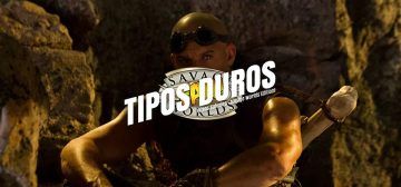 Una imagen de Riddick, el último de los furyanos, sentado con los brazos apoyados en las rodillas, sus célebres gafas colocadas en la frente y el brillo de sus ojos en una caverna oscura. Superpuesto, el logo de Tipos Duros con el sello Savage Worlds fan por debajo.