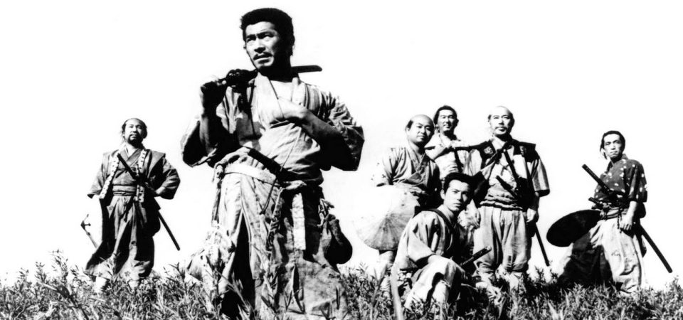 Fotografía en blanco y negro de los siete protagonistas de Los Siete Samurais, de Akira Kurosawa, con Toshir? Mifune al frente. Son todos hombres de mediana edad, curtidos, rudos, vestidos con ropas de diferente calidad y llevando al cinto sus daisho.