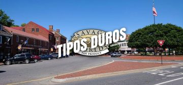 Una calle cualquiera de una zona residencial de una ciudad de estados unidos. Podría ser perfectamente de Wildspring, la ciudad que da nombre a la serie homónima. Alrededor de un cruce de amplias calzadas, edificios de uno o dos pisos, de ladrillo rojo visto y abundantes coches circulando o aparcando. Hay una rotonda central cubierta de árboles entre los que sobresale el mástil de una bandera de los Estados Unidos. Sobre la imagen está impreso el logo de Tipos Duros, el juego de rol: el texto Tipos Duros en letras blancas grandes y cuadradas, con una inclinación de unos 15º hacia la derecha y debajo, letra más pequeña pero con las mismas características Edición Aventura, todo girado unos 15º a contrarreloj y superpuesto al logo de Savage Worlds Fans Product.
