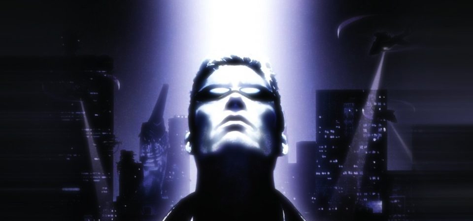 Ilustración de portada del videojuego de rol Deus Ex original, el del año 2000. La imagen muestra un primer plano de JC Denton, el protagonista, un hombre en la treintena, con gabardina y gafas de sol oscuras, mirando hacia arriba, desde donde le ilumina un poderoso haz de luz blanca. Detrás de él se pueden ver siluetas de edificios de una gran ciudad con luces encendidas mientras varios helicópteros parecen estar buscando algo en el suelo con potentes focos. La imagen es muy contrastada y sólo está en tonos de blanco, azul y negro.