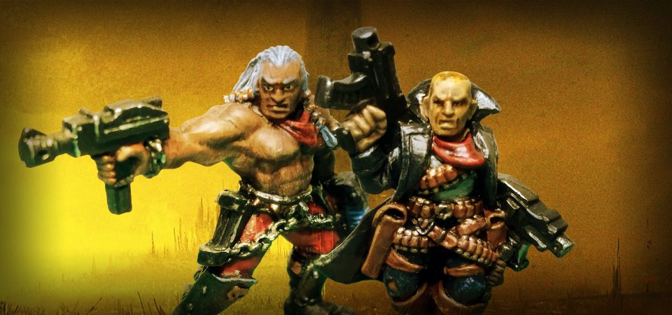 Fotografía de dos miniaturas de Necromunda. Dos pistoleros clásicos de metal convertidos en dramatis personae. Uno un tipo con el pecho descubierto, pelo largo blanco, pantalones rojos y grebas metálicas, con dos pistoleras y cinturón con cadenas de metal que le cuelgan por los muslos, que apunta hacia el lado izquierdo de la imagen con una pistola automática mientras sostiene una pistola de plasma con la otra mano. El otro otro pistolero con gabardina oscura, empuñando dos pistolas bolter y con la mayor parte del cuerpo cubierto de pistoleras y cartucheras llenas de munición.