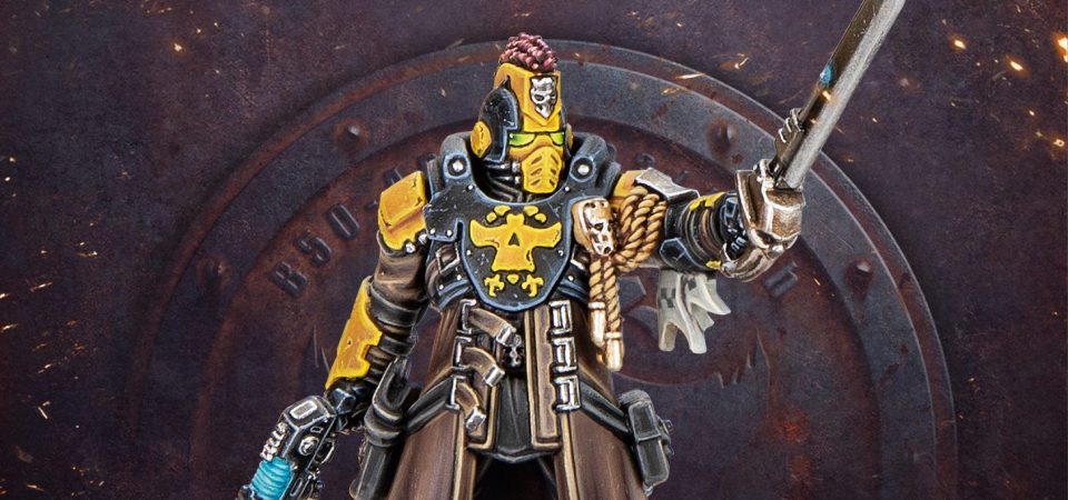 Fotografía en plano de tres cuartos de un capitán de los Palanite Enforcers. Va equipado con la placa pectoral, hombreras, casco y brazales típicos de la armadura enforcer, en colores azul-gris oscuro y amarillo anaranjado, además de una gabardina de cuerpo abierta. El casco lleva una cimera de fibras rojas. Del hombro izquierdo al pecho le cuelgan galardones en forma de insignias y cordón dorados. En la mano izquierda, levantada en actitud de señalar, empuña una espada de energía, mientras en la mano derecha, hacia abajo, lleva una pistola de plasma. Bajo la miniatura se puede ver el habitual emblema de Necromunda como el símbolo Imperial con forma de calavera en una placa de metal oxidado sobre una plancha del mismo material.
