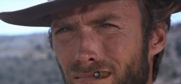 Primerísimo primer plano de Clint Eastwood en El bueno, el feo y el malo. Tiene los ojos entornados, un puro fino en la boca, el sombrero calado hasta media frente y su expresión patentada de haber chupado una cesta entera de limones.